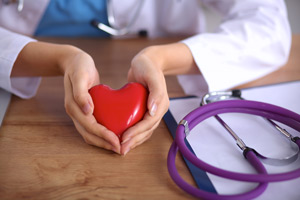 A female Physician is holding a heart shaped object